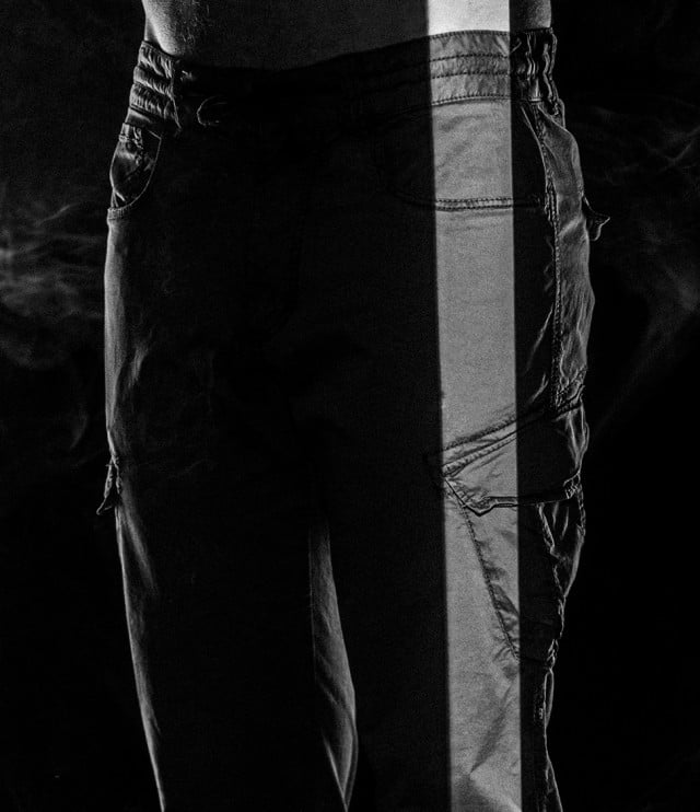 Eine Hose wird in dramatischem, vertikalem Lichtstreifen gezeigt, während der Rest im Schatten und leichtem Rauch verschwindet. Eine Hose wird in dramatischem, vertikalem Lichtstreifen gezeigt, während der Rest im Schatten und leichtem Rauch verschwindet.