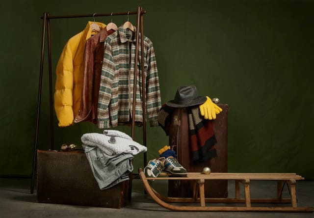 Das Bild zeigt eine stilvoll arrangierte Wintergarderobe mit Jacken, Accessoires und einem Holzschlitten. Das Bild zeigt eine stilvoll arrangierte Wintergarderobe mit Jacken, Accessoires und einem Holzschlitten.