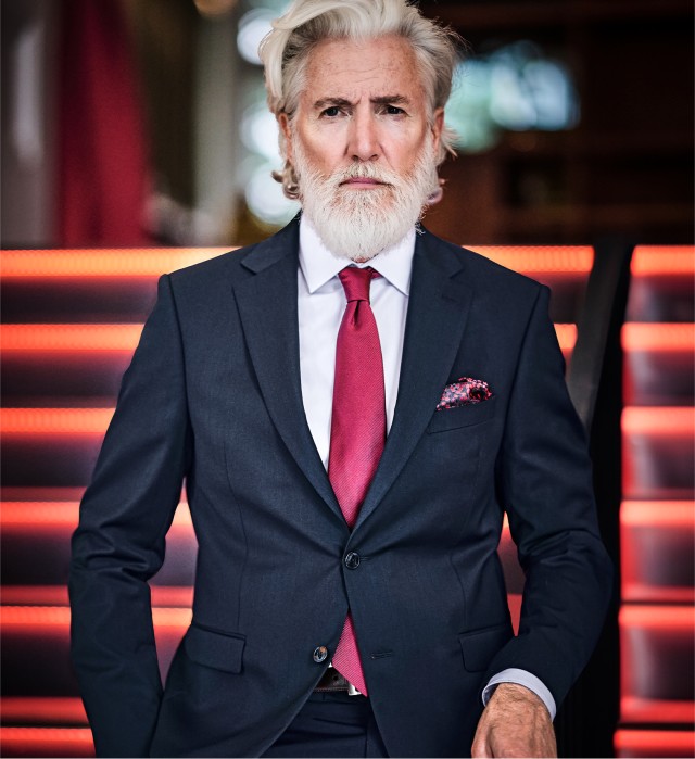 Ein Mann in einem eleganten schwarzen Anzug und roter Krawatte.