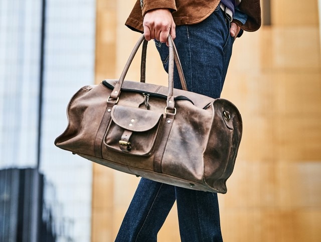 Ein Mann trägt eine große, braune Ledertasche in der Hand.