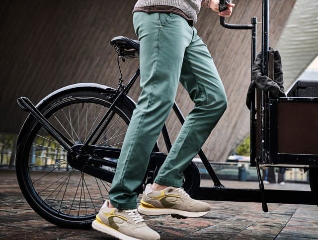 Zu sehen sind grüne Chinohosen, kombiniert mit beigefarbenen Sneakers mit gelben Akzenten.