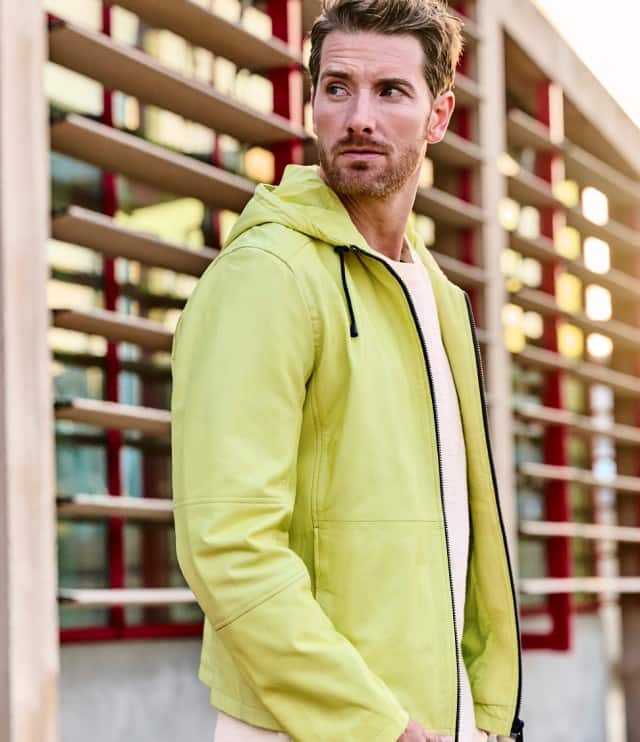 Ein Mann trägt eine gelbe LEderjacke und schaut neugierig zur Seite