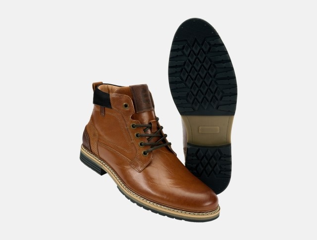 Ein Paar braune Lederboots mit schwarzer Sohle und dunklen Schnürsenkeln ist zu sehen, wobei ein Schuh seitlich steht und der andere die profilierte Sohle zeigt.