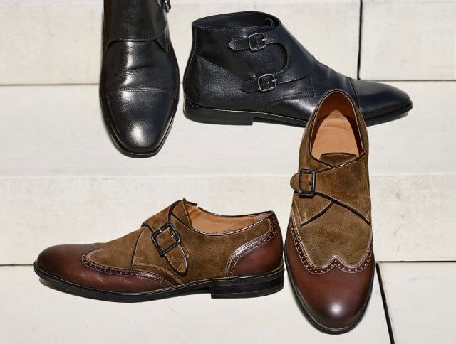 Auf dem Bild sind zwei Paar elegante Herrenschuhe zu sehen: ein schwarzes Paar mit doppelter Schnalle aus Glattleder und ein braun-sandfarbenes Paar aus kombiniertem Leder und Wildleder, beide auf hellen Stufen arrangiert.