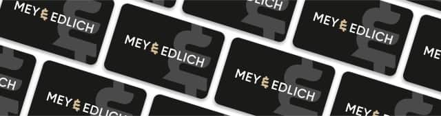 Auf dem Bild sind mehrere schwarze Karten mit dem weißen Schriftzug „MEY & EDLICH“ und dem Mey und Edlich Logo im Hintergrund in einem versetzten Muster angeordnet. Auf dem Bild sind mehrere schwarze Karten mit dem weißen Schriftzug „MEY & EDLICH“ und dem Mey und Edlich Logo im Hintergrund in einem versetzten Muster angeordnet.
