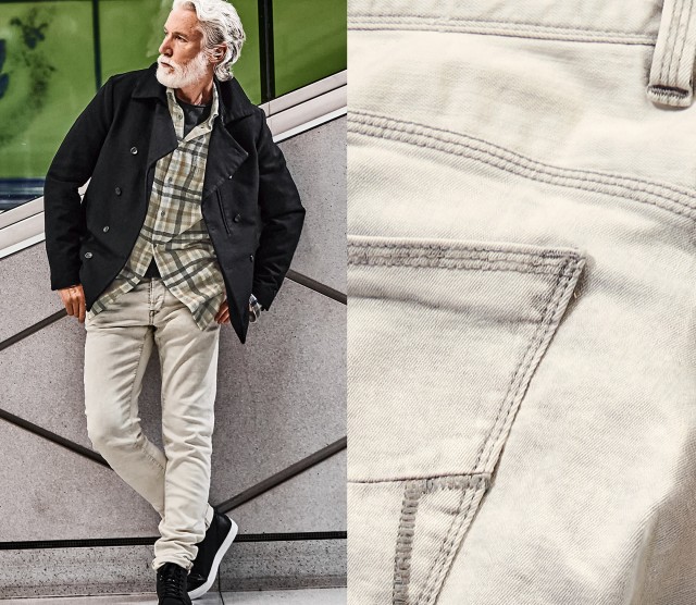 Mann mit heller Jeans lehnt an einer Wand