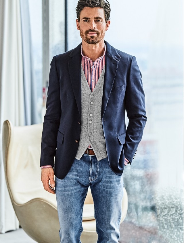 Business Casual gekleideter Mann der vor einem Fenster steht