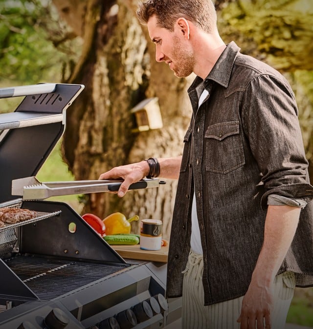Ein Mann steht im Outdoorbereich vor einem Grill der Marke Grillfürst.