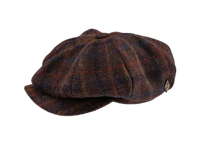 Auf dem Bild ist eine braun‑melierte Schiebermütze aus wolligem Stoff mit mehrfarbigem Muster und kleinem Metallemblem an der Seite zu sehen. Auf dem Bild ist eine braun‑melierte Schiebermütze aus wolligem Stoff mit mehrfarbigem Muster und kleinem Metallemblem an der Seite zu sehen.