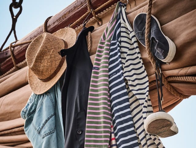 Eine Auswahl an Herrenbekleidung hängt über einem Segelmast