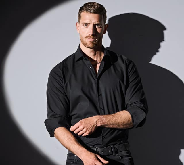 Das Bild zeigt ein schwarzes Hemd von Mey & Edlich in Regular Fit mit klassischem Kragen, das in einer eleganten, kontrastreichen Lichtstimmung modern und stilvoll präsentiert wird.