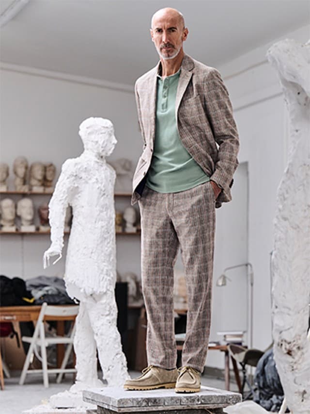Mann trägt einen gemusterten Anzug und steht in einem Atelier