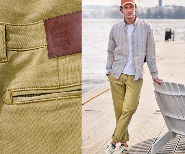 Das Bild zeigt links eine Nahaufnahme einer olivgrünen Hose mit braunem Lederetikett und rechts eine Person in gestreiftem Hemd, heller Hose, Kappe und Turnschuhen auf einem Steg am Wasser. Das Bild zeigt links eine Nahaufnahme einer olivgrünen Hose mit braunem Lederetikett und rechts eine Person in gestreiftem Hemd, heller Hose, Kappe und Turnschuhen auf einem Steg am Wasser.