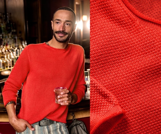 Das Bild zeigt einen Mann in einer Bar, der einen leuchtend roten Strickpullover trägt und ein Getränk in der Hand hält; daneben ist eine Detailaufnahme des Strickmusters des Pullovers zu sehen.