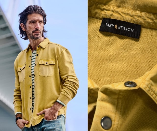 Ein Mann trägt ein gelbes Overshirt mit Brusttaschen über einem gestreiften Shirt, daneben ist eine Detailaufnahme des gelben Stoffes und des Mey‑&‑Edlich‑Labels zu sehen.