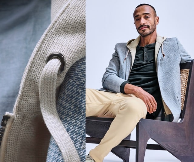 Ein Mann trägt ein hellgraues, strukturiertes Sakko mit eingenähter Kapuze über einem dunkelgrünen Henley‑Shirt, kombiniert mit hellbeigen Hosen.