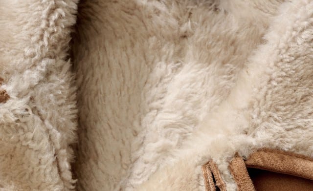 Das Bild zeigt eine Nahaufnahmefoto von weichem, beigefarbenem Lammfellfutter.