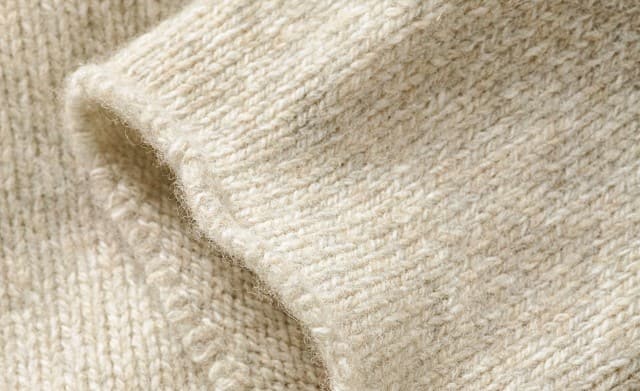 Das Bild zeigt eine Nahaufnahme von einem Wollpullover