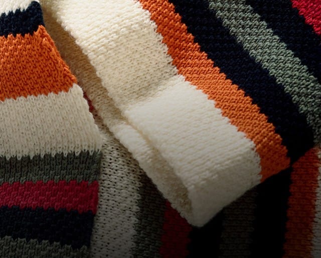 Das Bild zeigt einen Close Up von einem gestreift-bunten Strickhoodie