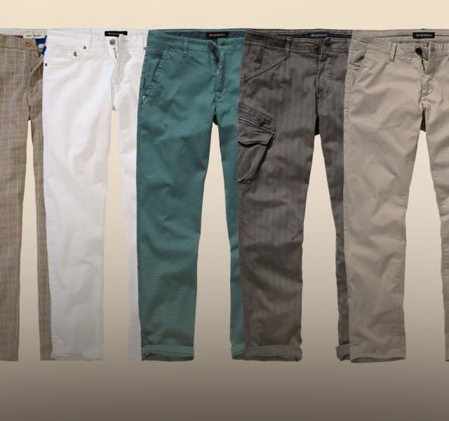 Zu sehen sind sechs unterschiedlich gefärbte und gestaltete Hosen, ordentlich nebeneinander vor einem neutralen Hintergrund, die verschiedene Stoffe, Schnitte und Details zeigen.