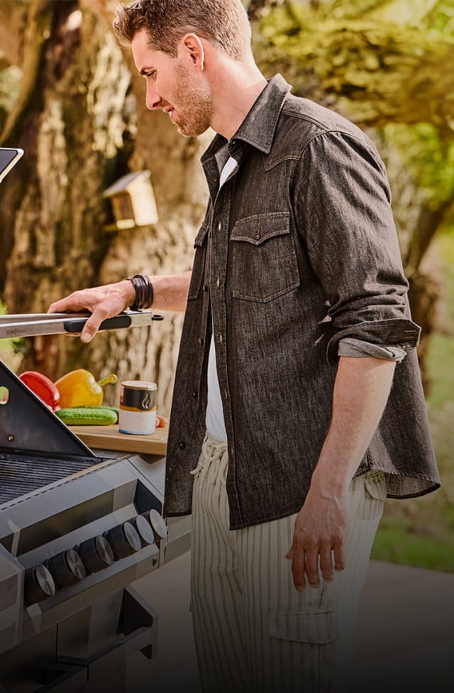 Ein Mann steht im Outdoorbereich vor einem Grill der Marke Grillfürst.