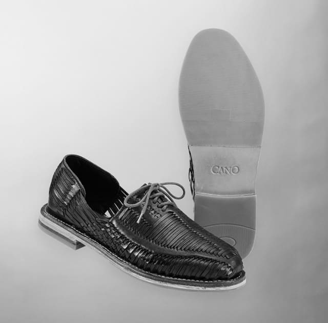 Zwei geflochtene Schnürschuhe werden in einer Studioaufnahme präsentiert, einer davon mit sichtbarer Schuhsohle.