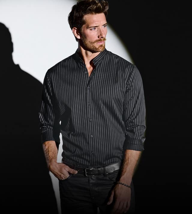 Auf dem Bild ist ein dunkelgrauer, grob gestrickter Pullover mit hohem Kragen zu sehen, der vor einem schwarz-weißen Hintergrund präsentiert wird.