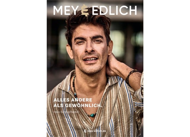 Das Titelbild zeigt einen Mann in einem gestreiften Hemd, der sich lässig durch die Haare fährt; um seinen Hals trägt er eine Holzkette