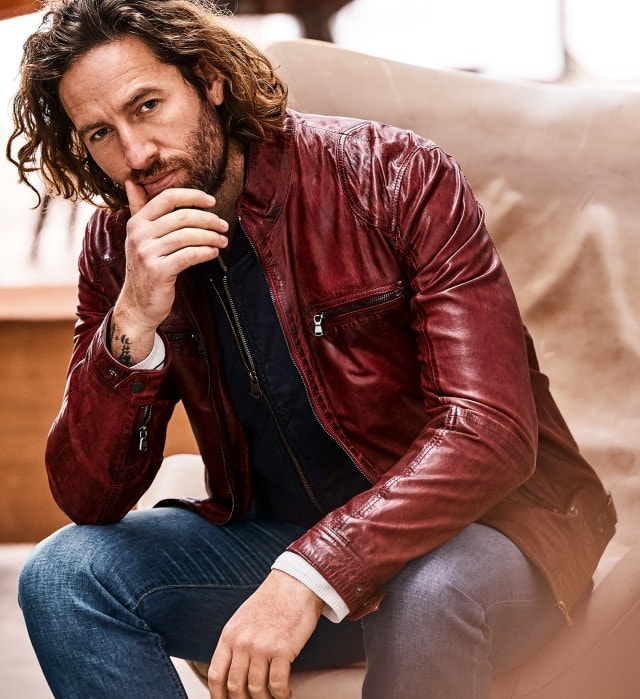 Mann mit roter Lederjacke sitzt auf einem Stuhl