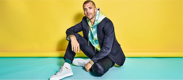 Ein Mann sitzt auf dem Boden in einen sportlich, sommerlichen Anzug.