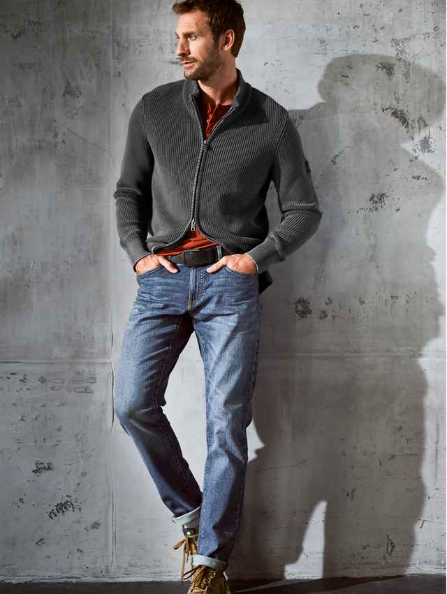 Smart Casual gekleideter Mann der an einer Steinwand lehnt