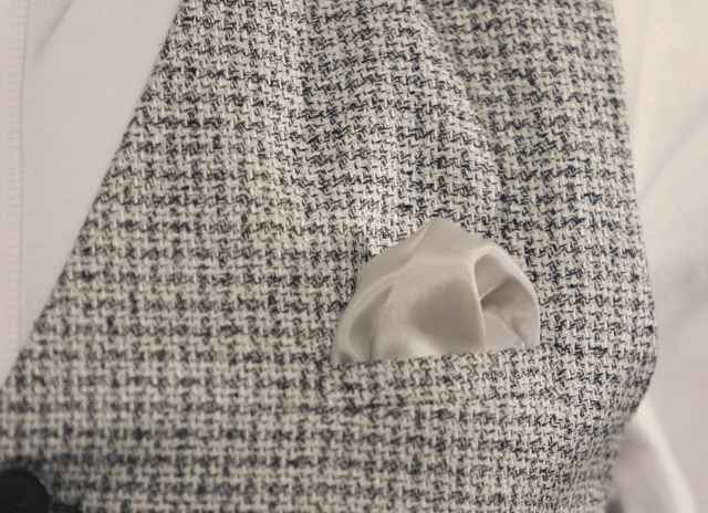 Nahaufnahme einer stilvollen Tweed-Weste mit eingestecktem cremefarbenem Einstecktuch.