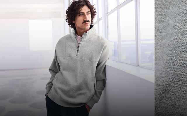Ein Mann trägt einen grauen Pullover mit Reißverschluss, daneben eine Nahaufnahme des Logos auf dem Stoff.