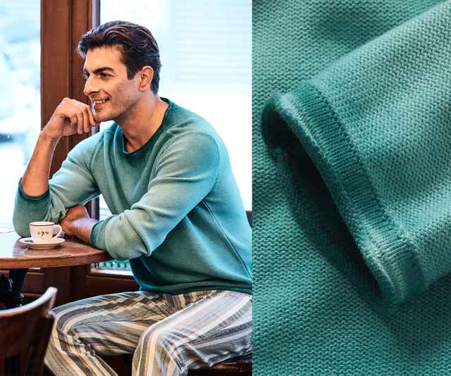 Mann in türkisfarbenem Pullover und gestreifter Hose sitzt mit Kaffee in einem Café; Nahaufnahme des Pullovers rechts.