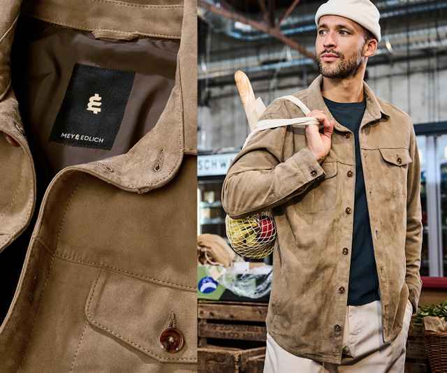 Mann mit beiger Jacke und Stofftasche über der Schulter, steht in einem Markt. Nahaufnahme des Jackenetiketts von Mey & Edlich links.
