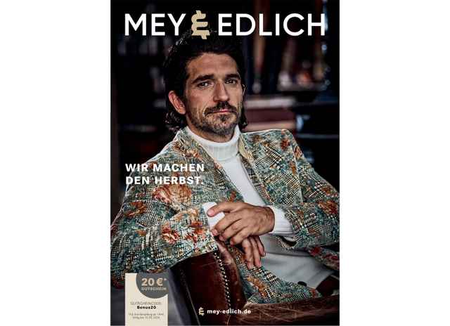 Mann in gemusterter Jacke sitzt, Mey & Edlich Katalog, Text: "Wir machen den Herbst", Gutschein unten links.