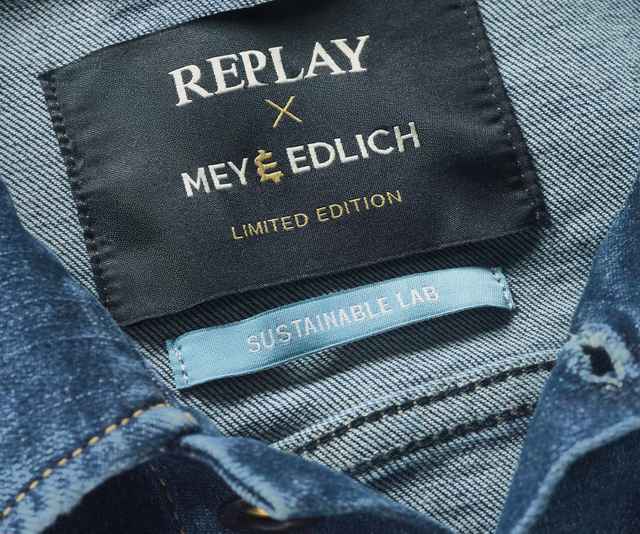 Nahaufnahme von einem Jeanshemd mit Etikett "REPLAY x MEY & EDLICH, LIMITED EDITION" und einem weiteren Etikett "SUSTAINABLE LAB".