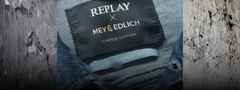 Nahaufnahme eines Jeansetiketts mit der Aufschrift "Replay x Mey & Edlich Limited Edition" und "Sustainable Lab". Hintergrund aus rauer Betonoptik.