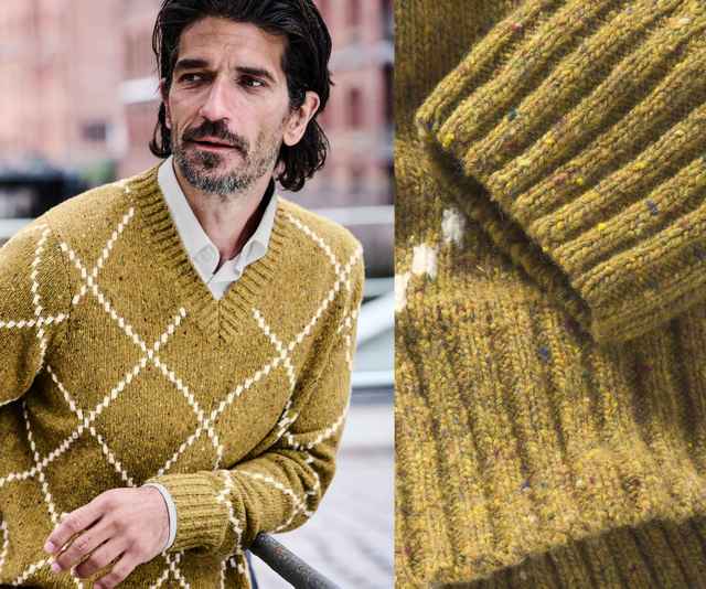 Mann mit braunem, kariertem Pullover aus Wolle. Detailaufnahme zeigt das Strickmuster und die Textur des Stoffes. Hintergrund urban.